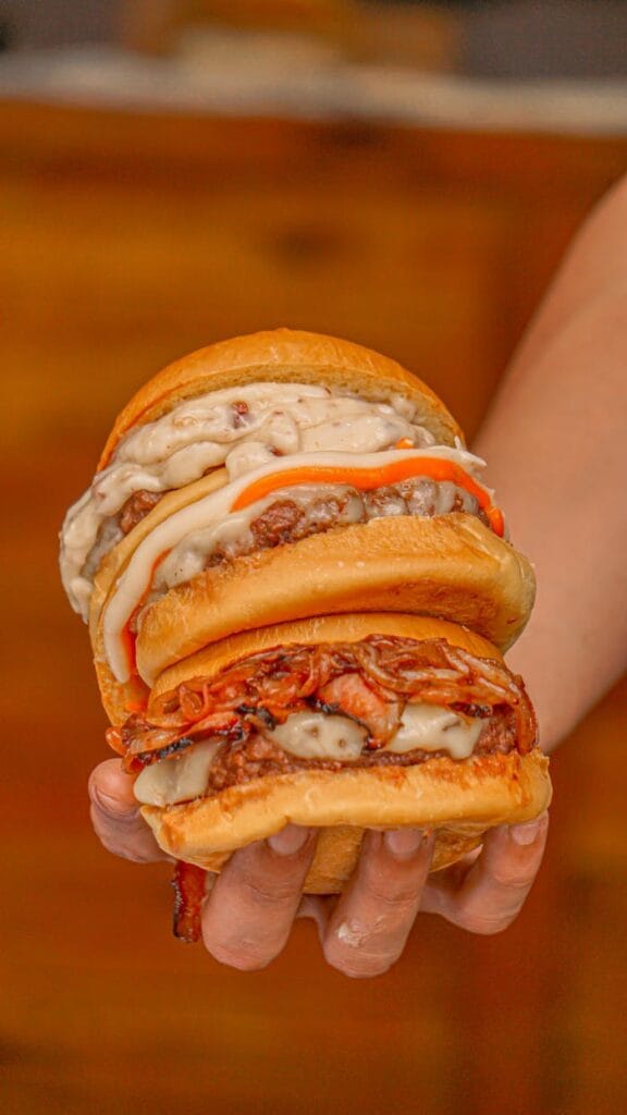 Mouth-watering double burger held in hand with melting cheese and toppings.